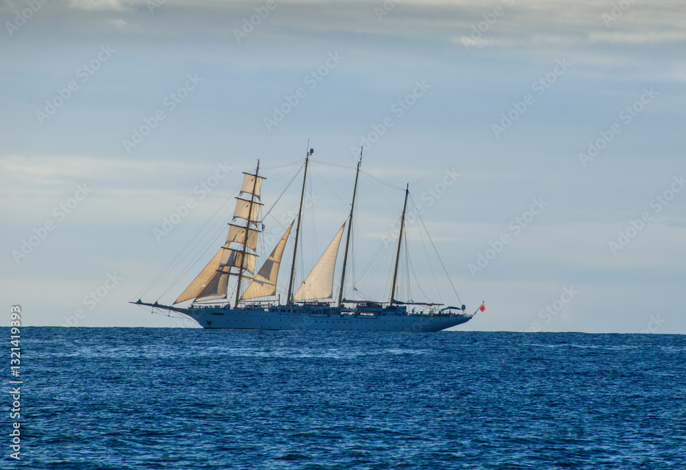 Tall ship with 4 masts on the sea at sunset