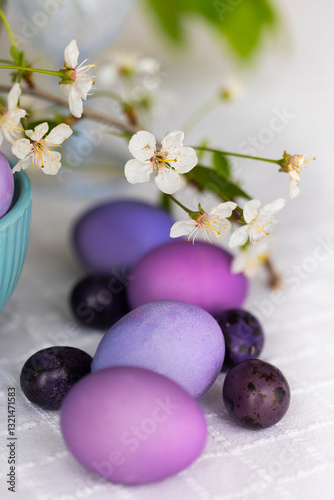 Easter eggs in shades of lilac and purple with green blooming branch in festive or holiday table