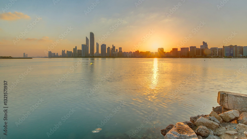Fototapeta premium Abu Dhabi city skyline on sunrise time with water reflection timelapse.