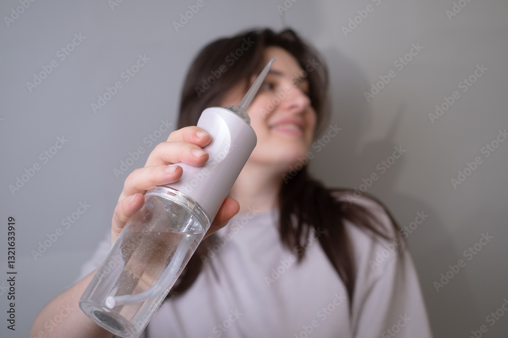 A woman uses a water flosser for deep cleaning, directing a powerful stream of water to remove plaque and maintain oral hygiene.