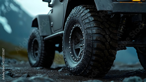 Close Up of Muddy Off Road Tire on 4x4 Vehicle in Rugged Mountain Landscape with Dark Grey and Black Wet Terrain