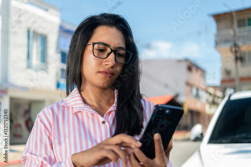 A Hispanic businesswoman with a serious and thoughtful expression reads online messages