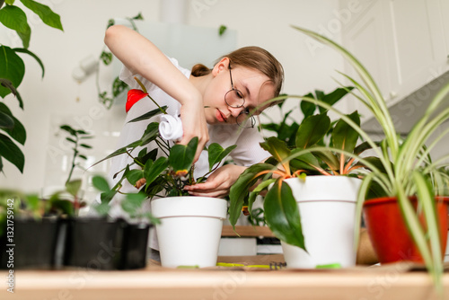Teen girl in casual attire gently cleaning houseplants in a modern interior.