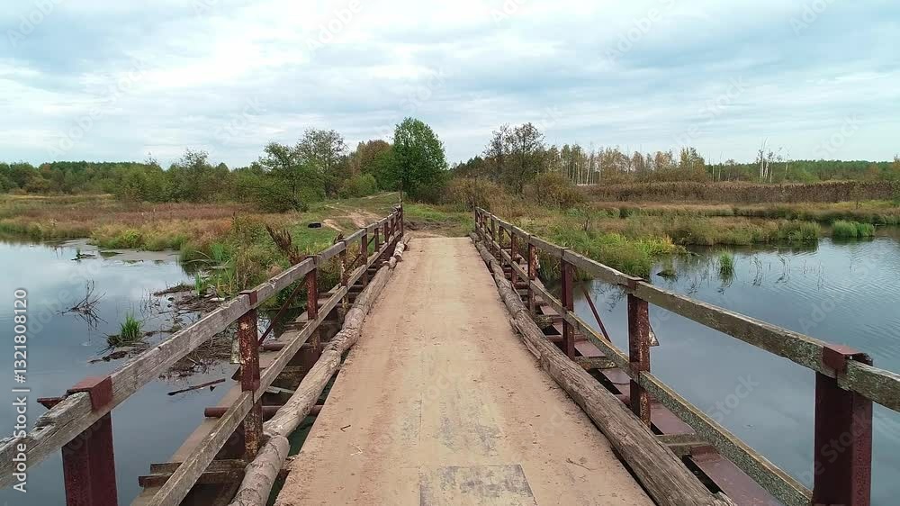 Bridge over a river with a view of the water. The bridge is old and rusted. Autumn colors of nature, the source of a forest stream and a small village on the edge of the lake. Bridge over a river with a view of the water. The bridge is old and rusted. Autumn colors of nature, the source of a forest stream and a small village on the edge of the lake.