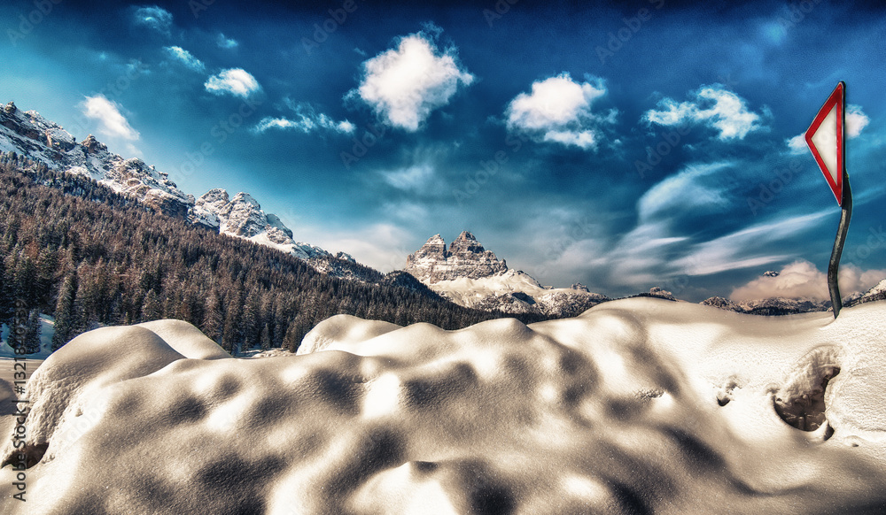 Mountain peak and snowy valley in winter season against a beautiful sunny blue sky