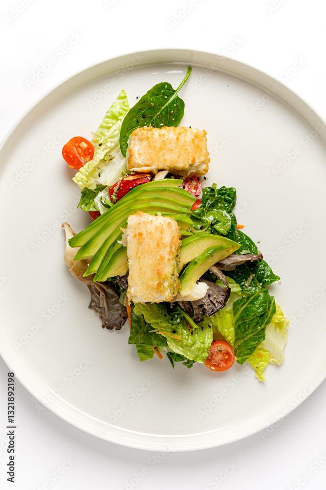 A vibrant salad with crispy tofu, avocado, fresh greens, and cherry tomatoes