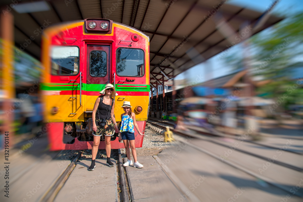 Mother and daughter exploring Maeklong Train Station, a unique tourist attraction in Thailand