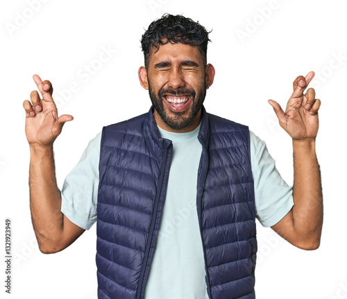 Young Hispanic man isolated crossing fingers for having luck