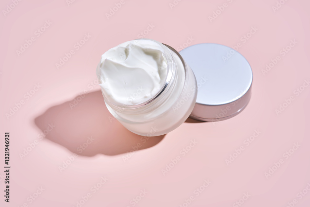 An open jar of cream with its texture on a pink background. An open jar of cream with its texture on a pink background.