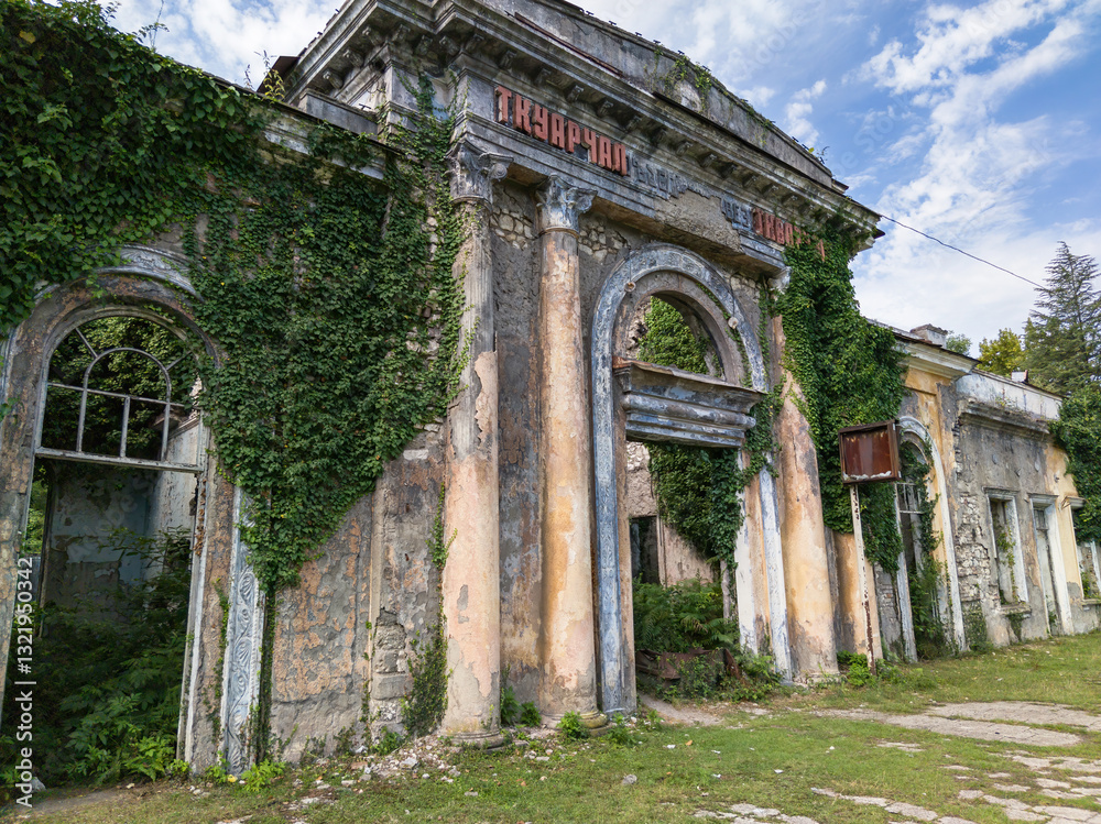 Abandoned railway station in Tkvarcheli city, Abkhazia. Old building ruins overgrown by grass in summer. Concept of war, grunge, architecture