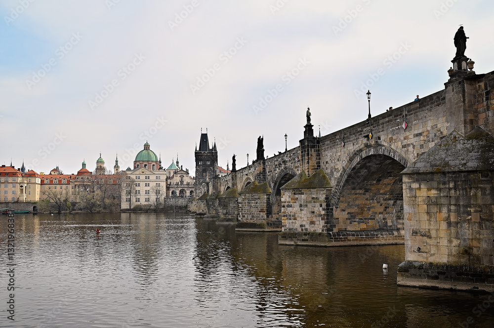 Fototapeta premium Charles bridge crossing vltava river in Prague with cloudy sky