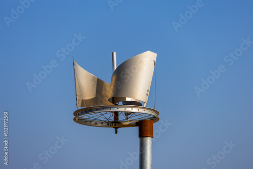 Repurposed Bicycle Wheel Wind Turbine Against a Clear Blue Sky
