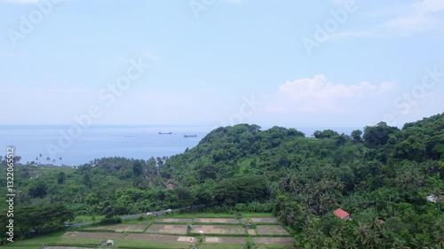 Aerial view of multiple cargo ships and vessels floating on a calm blue ocean under a clear sky. The vast seascape creates a peaceful and serene maritime scene, ideal for global trade, shipping indust