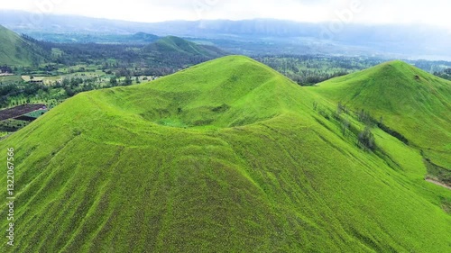 aerial view of green hills peak with grassland and mountain views of Wurung Crater, Indonesia. Aerial shot of the green grassy peak of the mountain crater.