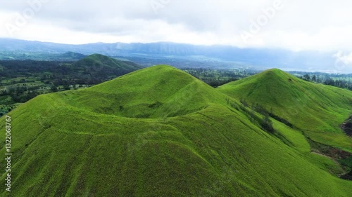 aerial view of green hills peak with grassland and mountain views of Wurung Crater, Indonesia. Aerial shot of the green grassy peak of the mountain crater.