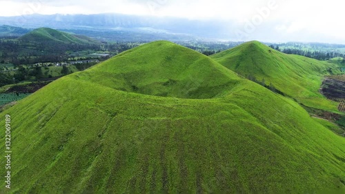 aerial view of green hills peak with grassland and mountain views of Wurung Crater, Indonesia. Aerial shot of the green grassy peak of the mountain crater.