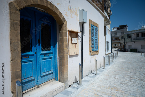 Fototapeta Naklejka Na Ścianę i Meble -  Blue doors and windows of white buildings in Greek style in Paphos, Cyprus. Mediterranean architecture and city streets. A concept of tourism, coastal beauty, and timeless travel inspiration