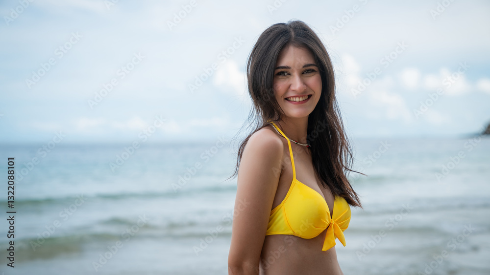 A woman in a yellow bikini is smiling at the camera while standing on a beach A woman in a yellow bikini is smiling at the camera while standing on a beach