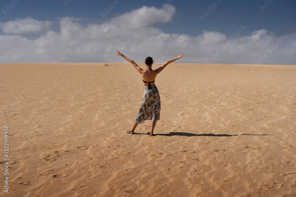 Joyful woman stands in sandy dessert of Fuerteventura, arms raised in pure happiness. clouds, sun, and her all-inclusive wristband symbolize ultimate freedom, relaxation, and perfect holiday escape Joyful woman stands in sandy dessert of Fuerteventura, arms raised in pure happiness. clouds, sun, and her all-inclusive wristband symbolize ultimate freedom, relaxation, and perfect holiday escape