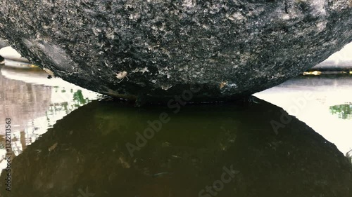 Small fish swim in the fountain under a large stone ball