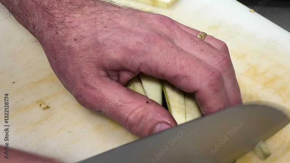 Taille en lamelles d'aubergine sur la planche a découpé, couteau aiguisé | gros plan