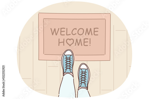 Rug with inscription welcome home on threshold near entrance to apartment and feet of man in boots