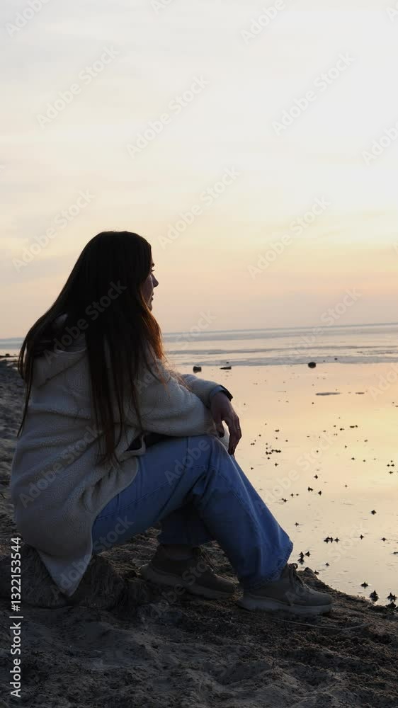 A woman is seated on the sandy beach, gazing at the vibrant sunset reflecting off the calm ocean. The serene atmosphere creates a moment of peaceful contemplation by the water's edge. A woman is seated on the sandy beach, gazing at the vibrant sunset reflecting off the calm ocean. The serene atmosphere creates a moment of peaceful contemplation by the water's edge.