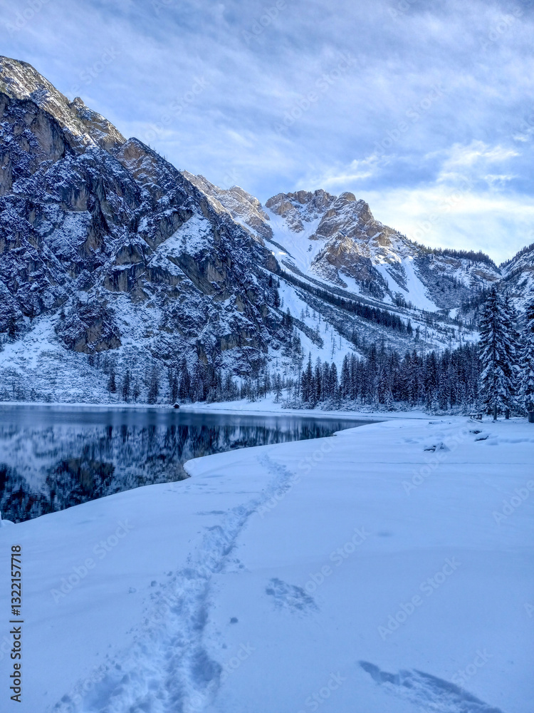 Lake Braies with its snowy rocky mountains clear blue water that reflects the mountain