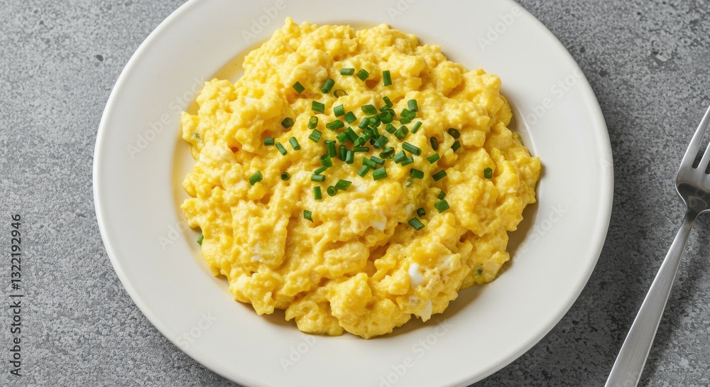 Creamy scrambled eggs, fluffy texture, white plate, gray background, chopped chives garnish, bright yellow color, comfort food, breakfast dish, close-up view, simple presentation, high-contrast lighti Creamy scrambled eggs, fluffy texture, white plate, gray background, chopped chives garnish, bright yellow color, comfort food, breakfast dish, close-up view, simple presentation, high-contrast lighti