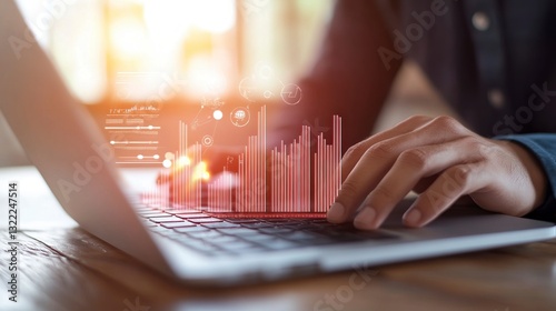 Person's hands hover over laptop keyboard, interacting with a vibrant red and orange digital graph projection. Warm lighting illuminates the scene