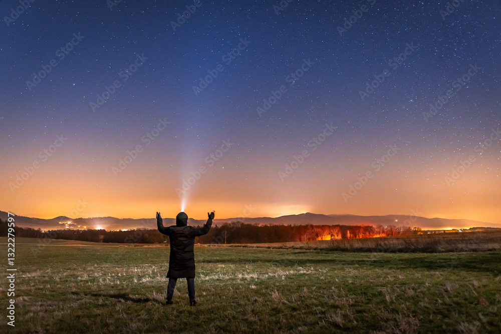 Night landscape, young man admires the stars in the sky above the mountains. Long exposure of the night sky.