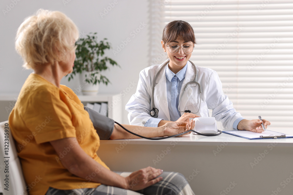 Obraz premium Doctor measuring senior woman's blood pressure during appointment in hospital