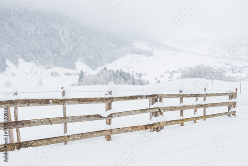 Obraz na płótnie Snow-covered wooden fence on a mountain pasture. Winter landscape on a mountain hiking trail on a cloudy and foggy day. w salonie