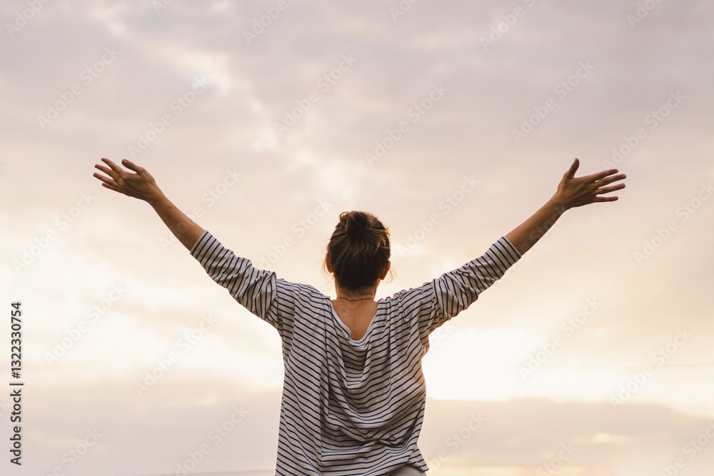 Woman with outstretched arms embracing sky and freedom at sunset Woman with outstretched arms embracing sky and freedom at sunset