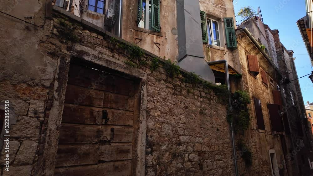 Clothes hanging on a clothesline. Narrow street scenery with beautiful historic residential apartments. Lights and shadows on the street in the old town of Rovinj, Croatia. Looking up. Clothes hanging on a clothesline. Narrow street scenery with beautiful historic residential apartments. Lights and shadows on the street in the old town of Rovinj, Croatia. Looking up.