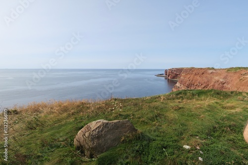 Wallpaper Mural Ein grauer Felsen liegt am Klippenrand des Oberlands der Hochseeinsel Helgoland. Im Hintergrund sind die roten Bundsandsteinfelsen zu sehen, für die die Nordseeinsel bekannt ist.  Torontodigital.ca