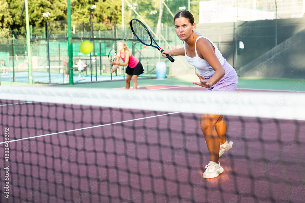 Fototapeta premium Young woman in shorts playing tennis on court. Racket sport training outdoors.