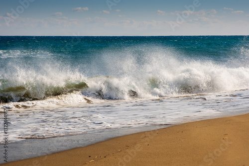 Fototapeta Naklejka Na Ścianę i Meble -  Sea wave breaks on sandy beach with clouds sky on Mediterranean coast of Mersin province, Atakent