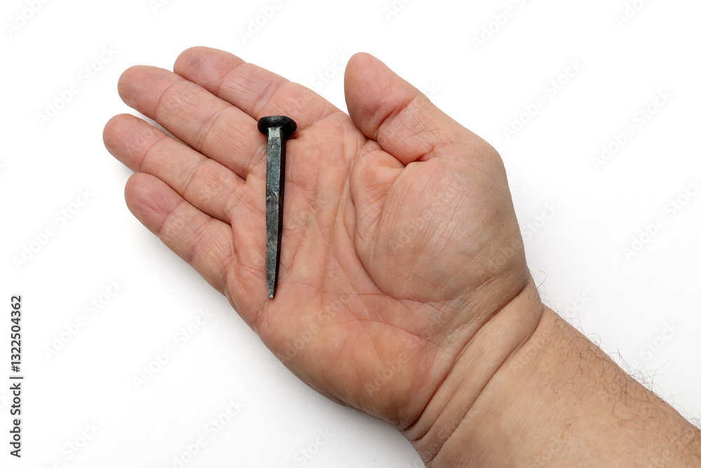 Hand Forged Wrought Iron Rose Head Nail Held in Hand, the Nail of Sacrifice and Easter Crucifixion, Isolated on White Background Hand Forged Wrought Iron Rose Head Nail Held in Hand, the Nail of Sacrifice and Easter Crucifixion, Isolated on White Background