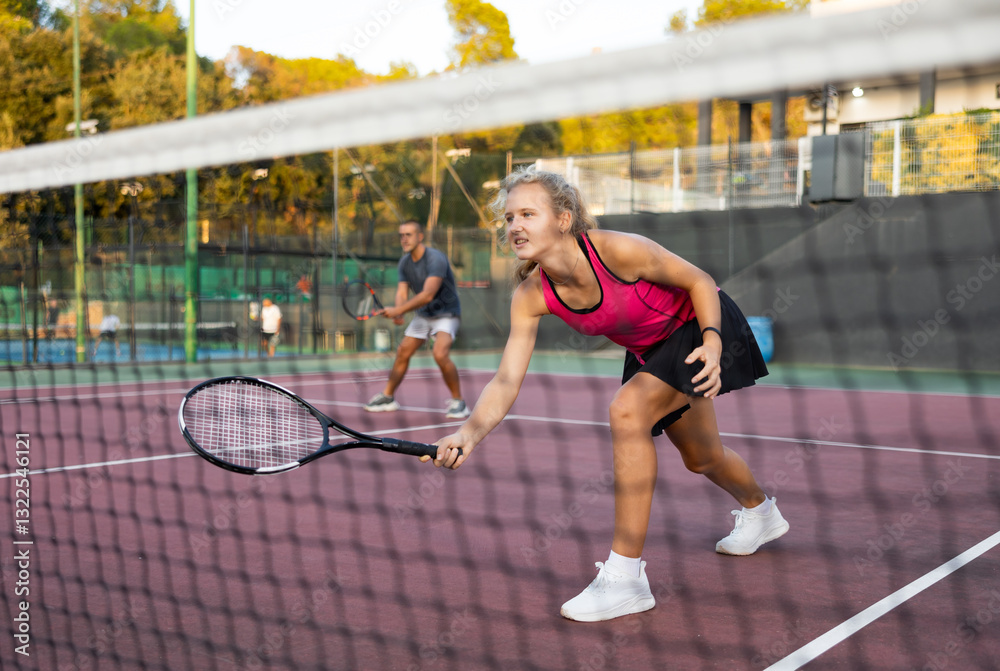 Fototapeta premium Young woman in skirt playing tennis on court. Racket sport training outdoors.