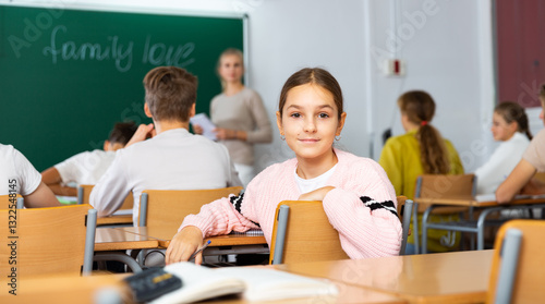 Portrait of smiling positive schoolgirl posing in classroom during lesson in secondary school