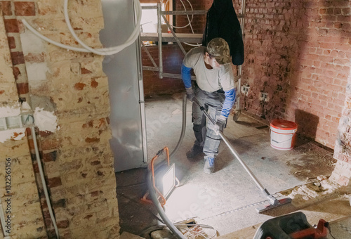 A young man vacuums the landing in a repair room.