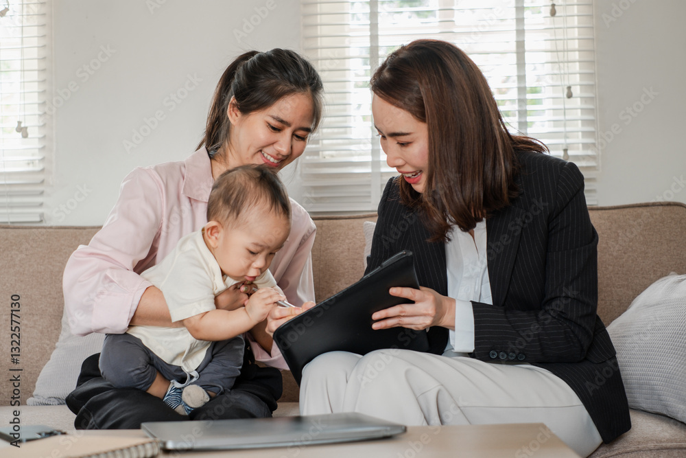 Fototapeta premium Two women and a baby in a home setting, discussing business with a tablet, showcasing work-life balance and modern family dynamics.