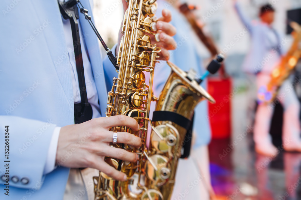 Fototapeta premium Concert view of saxophonist musician, saxophone sax player with vocalist and musical band during jazz orchestra show performing music on a stage in the scene lights, concert in a musical club hall