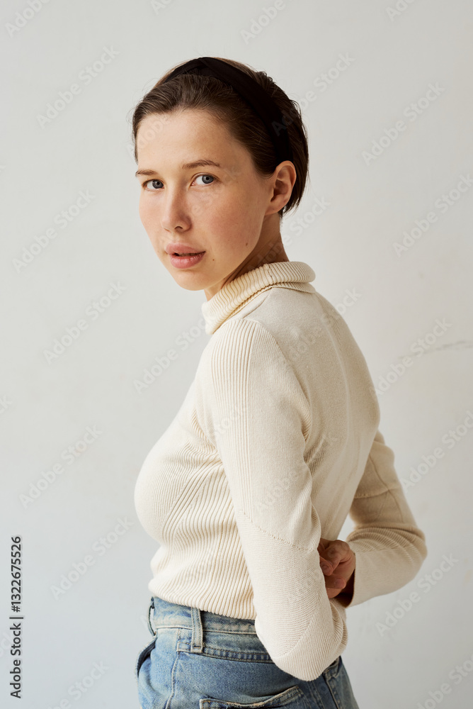 Young woman poses in light sweater and jeans indoors Young woman poses in light sweater and jeans indoors