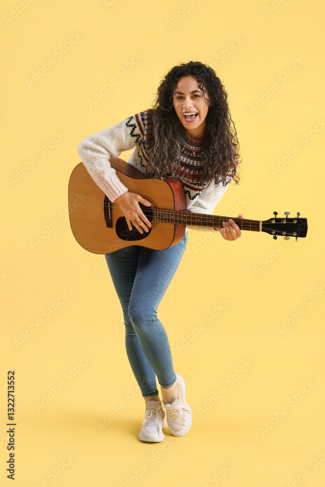 Young African-American woman playing acoustic guitar on yellow background Young African-American woman playing acoustic guitar on yellow background
