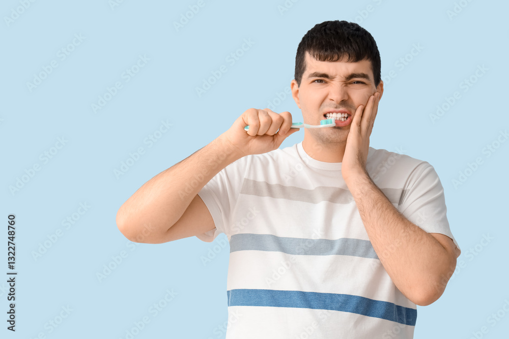 Young man with brush suffering from toothache on blue background Young man with brush suffering from toothache on blue background