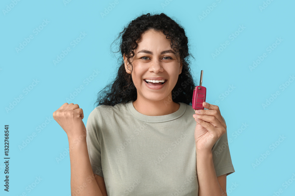 Happy young African-American woman with car key on blue background Happy young African-American woman with car key on blue background