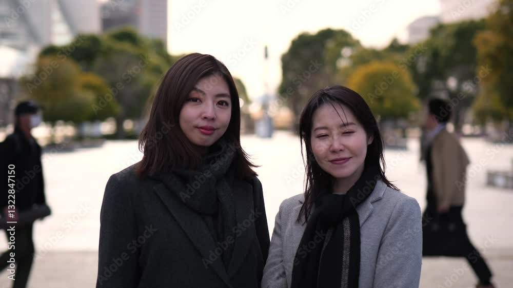 夕暮れの街を背景に笑顔の二人のビジネスウーマンのズームインポートレート