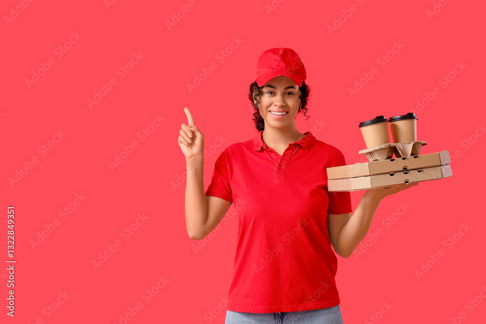 Female African-American courier pointing at something with cardboard boxes of tasty pizza and paper cups of coffee on red background Female African-American courier pointing at something with cardboard boxes of tasty pizza and paper cups of coffee on red background